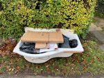 Plastic bath, packaging, waste plastic bath; cardboard & polystyrene packaging, plastic film & empty sealant tubes, bucket of rubble, laminate flooring. CB2 - removed for £140