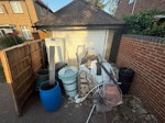 Garden and house rubbish All items from the brown fence to the brick wall. Includes plastic bins, water butts, plastic pots, rolls of old vinyl flooring small pallet of plasterboard and other building waste, fridge freezer. SL3 - removed for £155