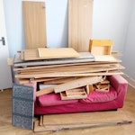 Two-seater sofa, wood, tiles. Hi, as you can see from the picture, one two-seat sofa (damaged), five bathroom floor tiles, a half-box of flooring, one rug, two dismantled wardrobes, and some shelving. SE25 - removed for £193