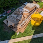 Mixed light waste A mix of mostly light household and renovation waste located in the front garden for easy access. Includes:
Cardboard & Paper: Large quantity of flattened cardboard boxes and paper floor protector.
Builders bags: 8 unopened/surplus bags of construction materials (multi-finish plaster, tile adhesive, etc.).
General & Recyclable waste: Approx. 4-5 bags of mixed light waste (rubbish and recycling).
Wood: 2 sheets of plywood and some timber offcuts. E16 - removed for £176