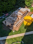 Mixed light waste A mix of mostly light household and renovation waste located in the front garden for easy access. Includes:
Cardboard & Paper: Large quantity of flattened cardboard boxes and paper floor protector.
Builders bags: 8 unopened/surplus bags of construction materials (multi-finish plaster, tile adhesive, etc.).
General & Recyclable waste: Approx. 4-5 bags of mixed light waste (rubbish and recycling).
Wood: 2 sheets of plywood and some timber offcuts. E16 - removed for £176