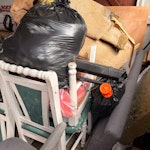 Small garage pile Garage clearance of mixed household and furniture waste. Includes approx. 3–4 dining chairs (wood and upholstered), a small glass coffee table, one office chair, a rowing machine, rolled carpet/rug material, several full bin bags, a vacuum cleaner, lamp, and loose timber/wood pieces. Items are stacked in one area and accessible from the garage entrance. No hazardous materials. No dismantling required. BS39 - removed for £200
