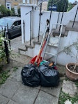 2 bags/ladder/brooms/2 buckets Bag 1 (red tag) contains: box of blades/sharps, caddy with batteries+print cartridges, metal. Could be recycled?
Bag 2 contains general household rubbish
Red bucket with various old brooms
Old watering can
Metal ladder SE10 - removed for £43